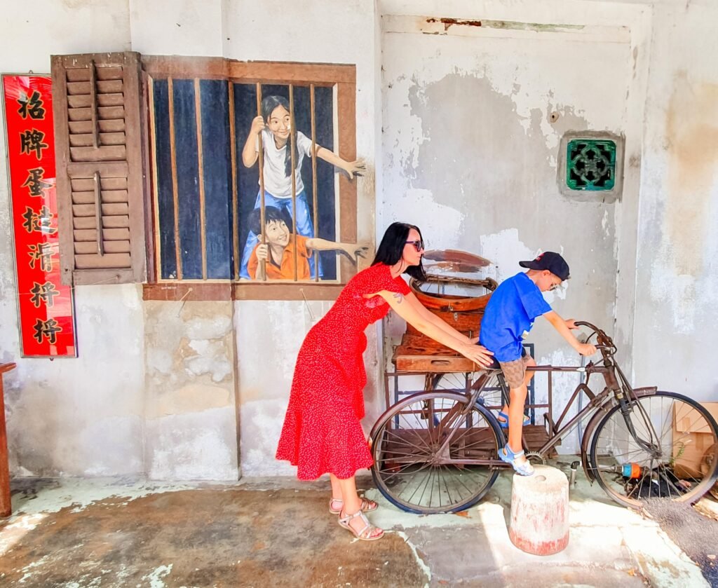 Mother and son exploring street art on a vintage bicycle in George Town, Penang