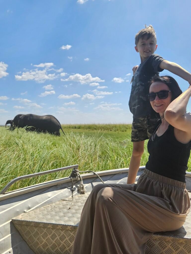 Our son and I on a boat safari in Botswana, watching an elephant graze in the tall riverside grass behind us
