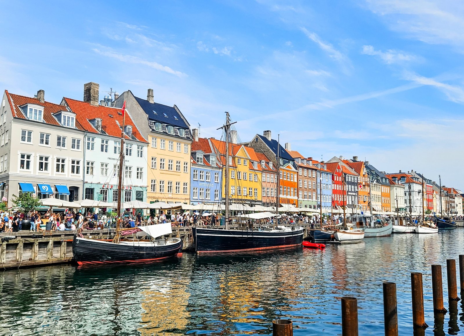 The colourful waterfront houses and historic wooden sailing boats of Nyhavn, Copenhagen, on a sunny day