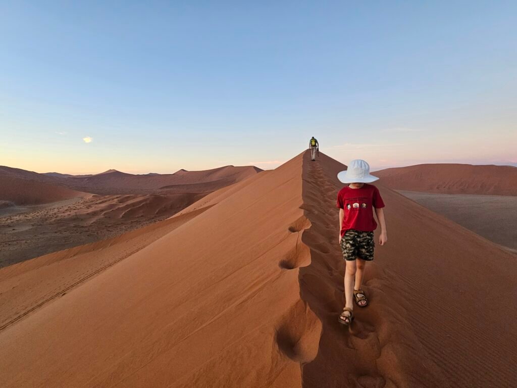 Family climbing the red sand dunes of Sossusvlei with kids