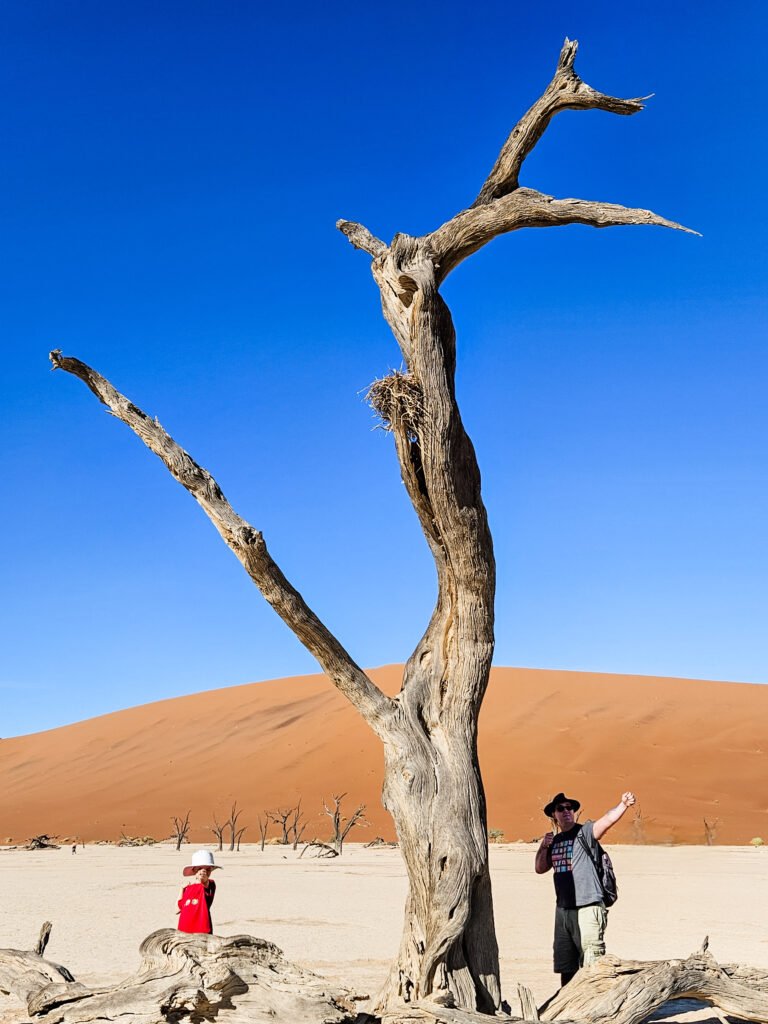 Family walking across the cracked white clay pan at Deadvlei, Namibia
