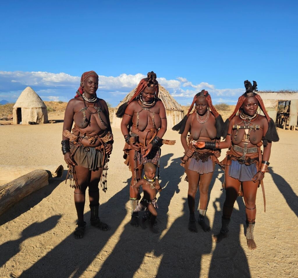 Child engaging with Himba community members during a cultural visit