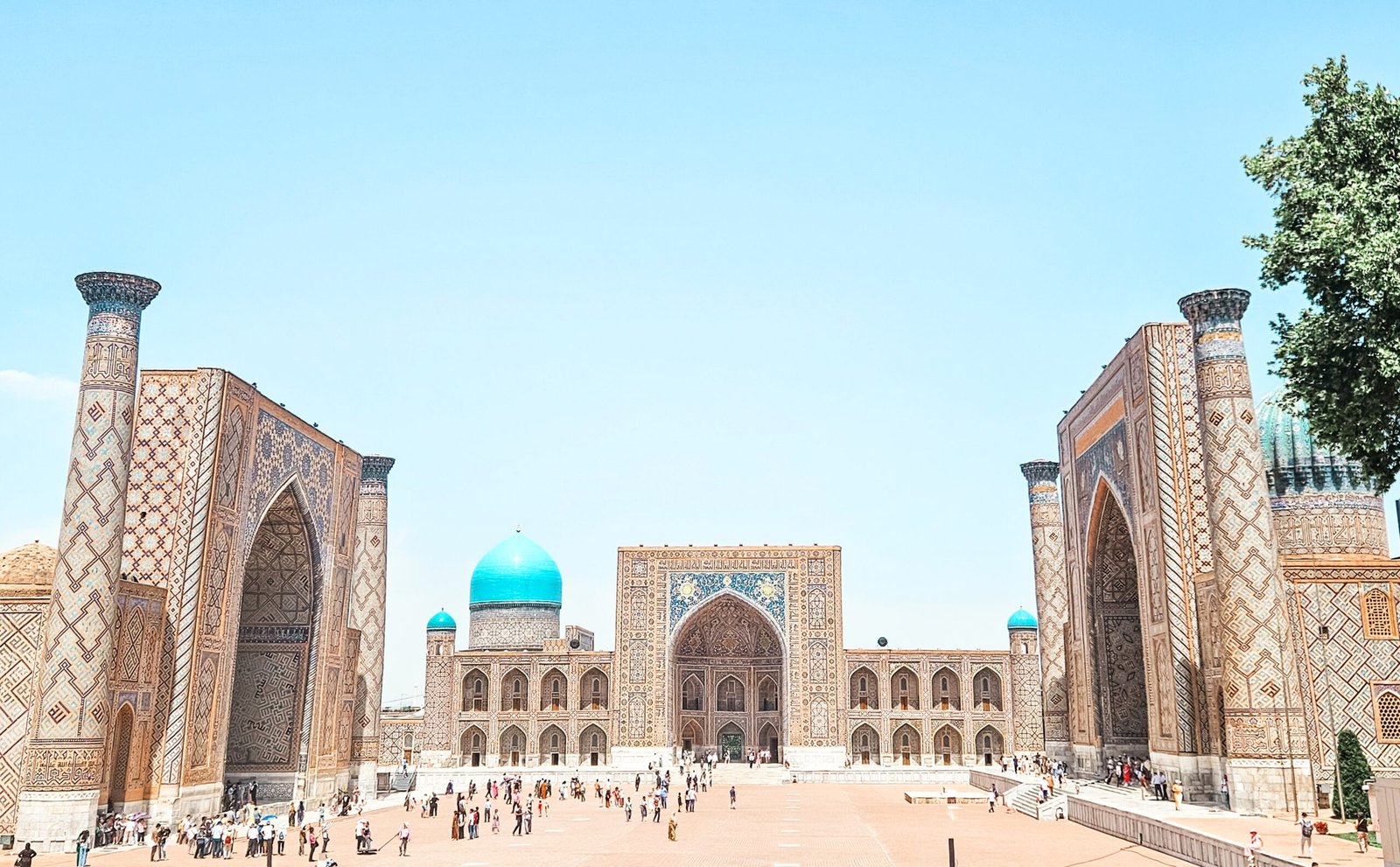 Family in front of Registan Square's turquoise-tiled madrasas in Samarkand