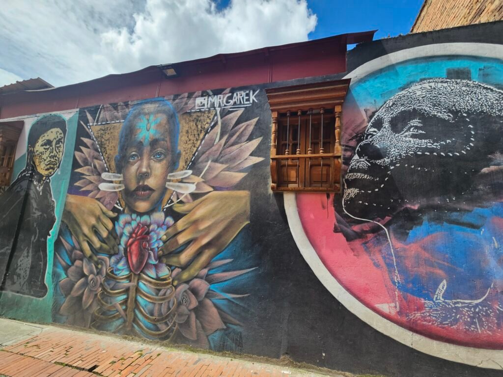 Surreal street art mural of faces and a heart in La Candelaria, Bogotá