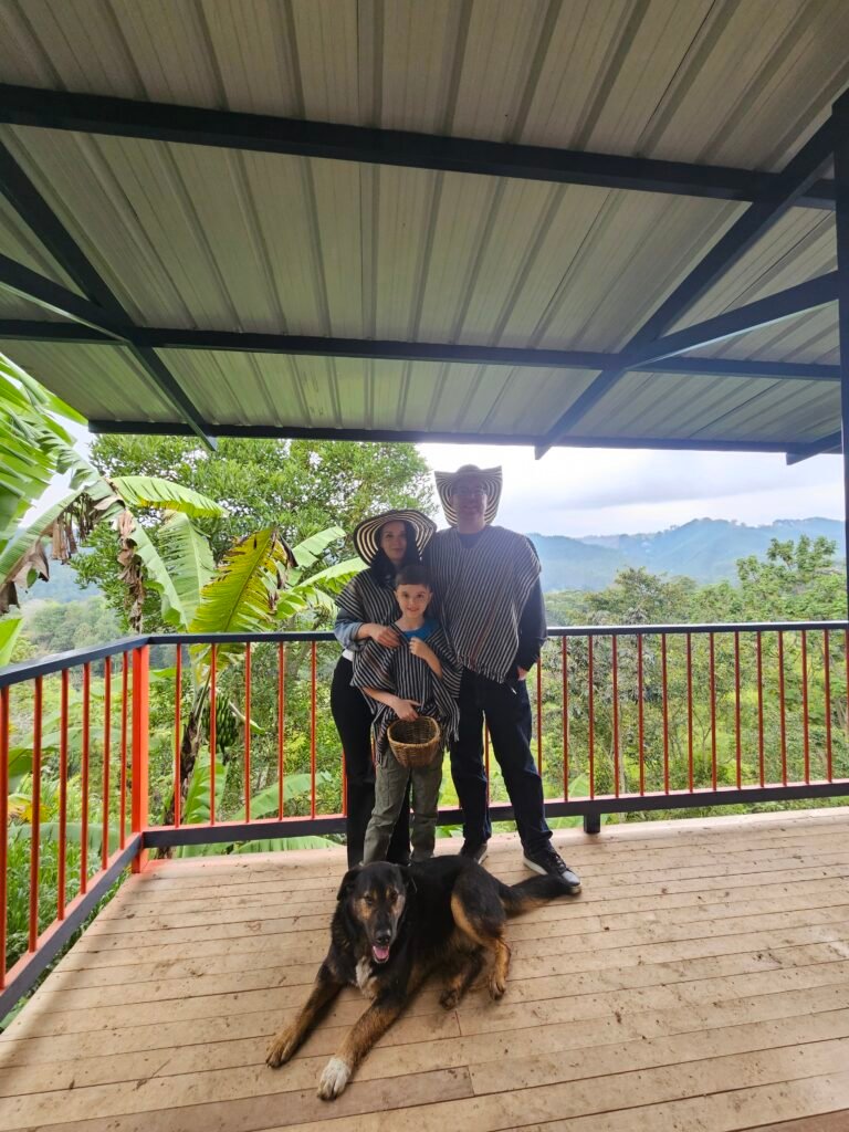Family and their dog on a lookout deck overlooking the hills of a Salento coffee finca