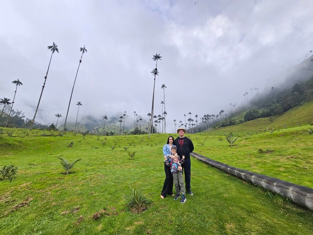 Woman walking along a grassy trail past wax palms in the Cocora Valley