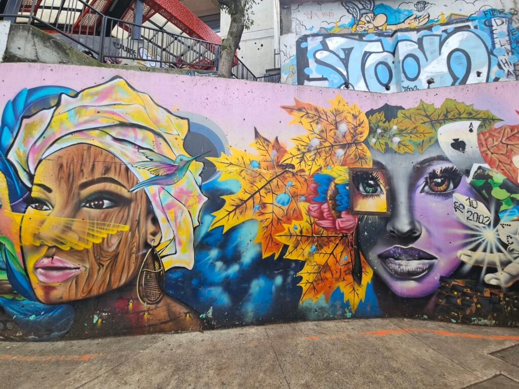 Colourful street art mural of two women's faces with a hummingbird in Comuna 13, Medellín