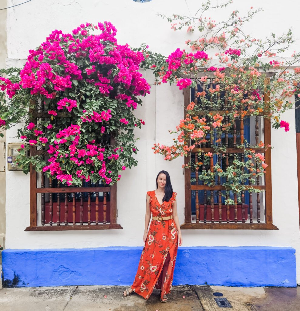 Woman posing in a floral orange jumpsuit beside a bougainvillea-covered wall in Cartagena's old town