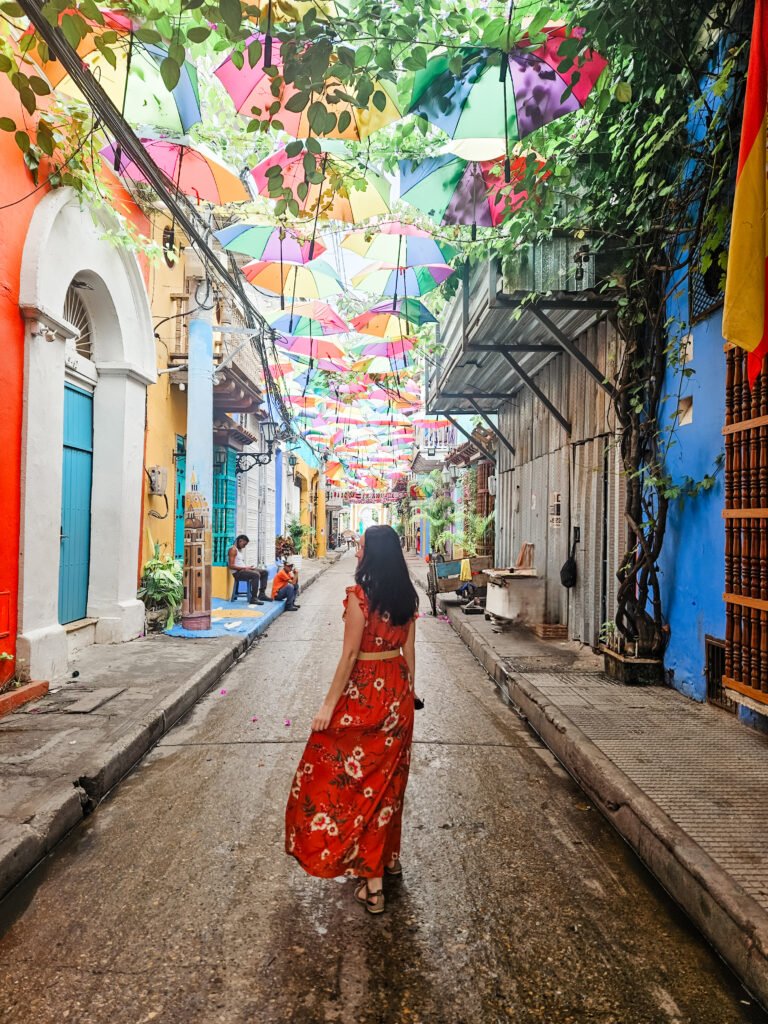 Woman walking beneath a canopy of colourful umbrellas in Getsemaní, Cartagena