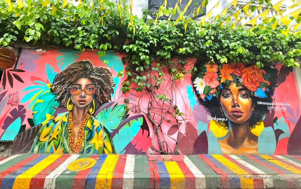 Colourful street art mural of two women framed by greenery in Getsemaní, Cartagena