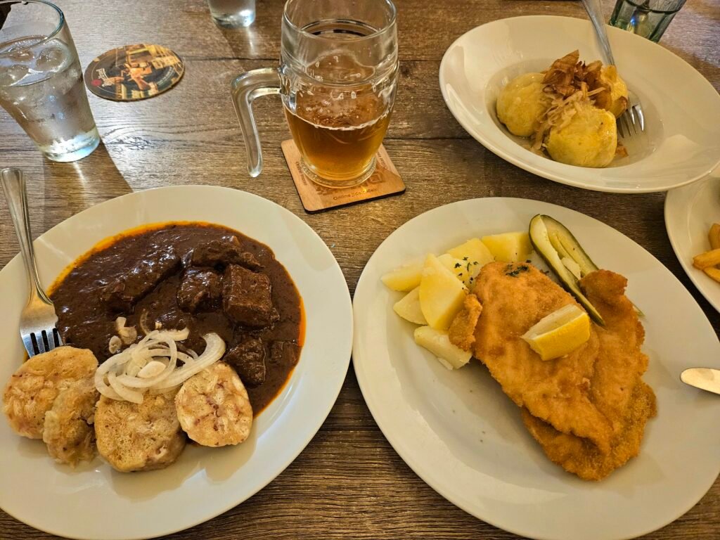 Traditional Czech dishes including goulash and fried schnitzel served with potato dumplings