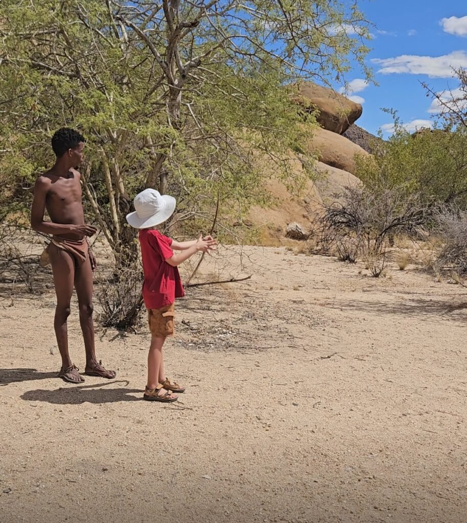 Child learning traditional bushcraft skills from San guides