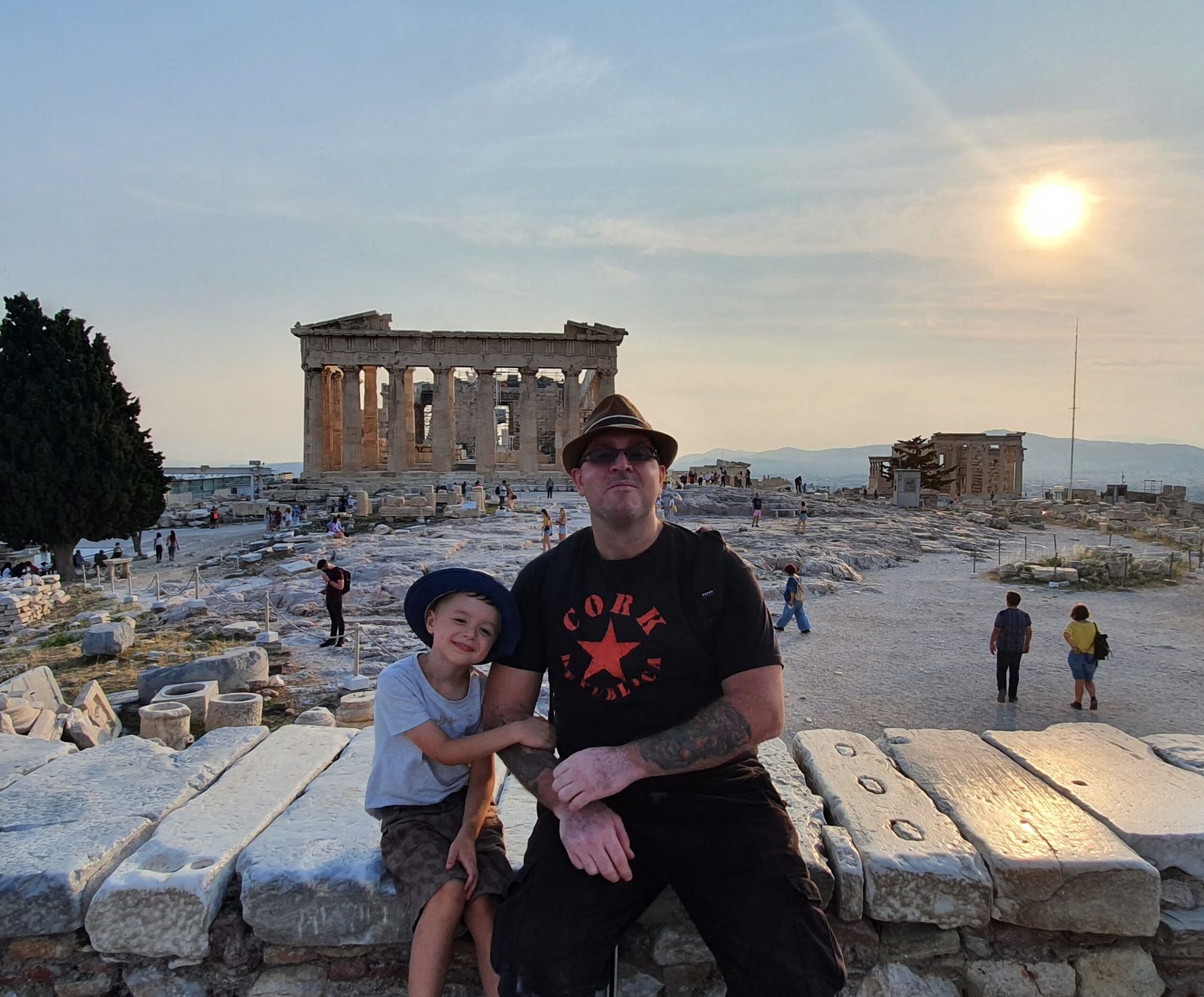 Father and young son sitting in front of the Parthenon on the Acropolis in Athens during our first year of worldschooling