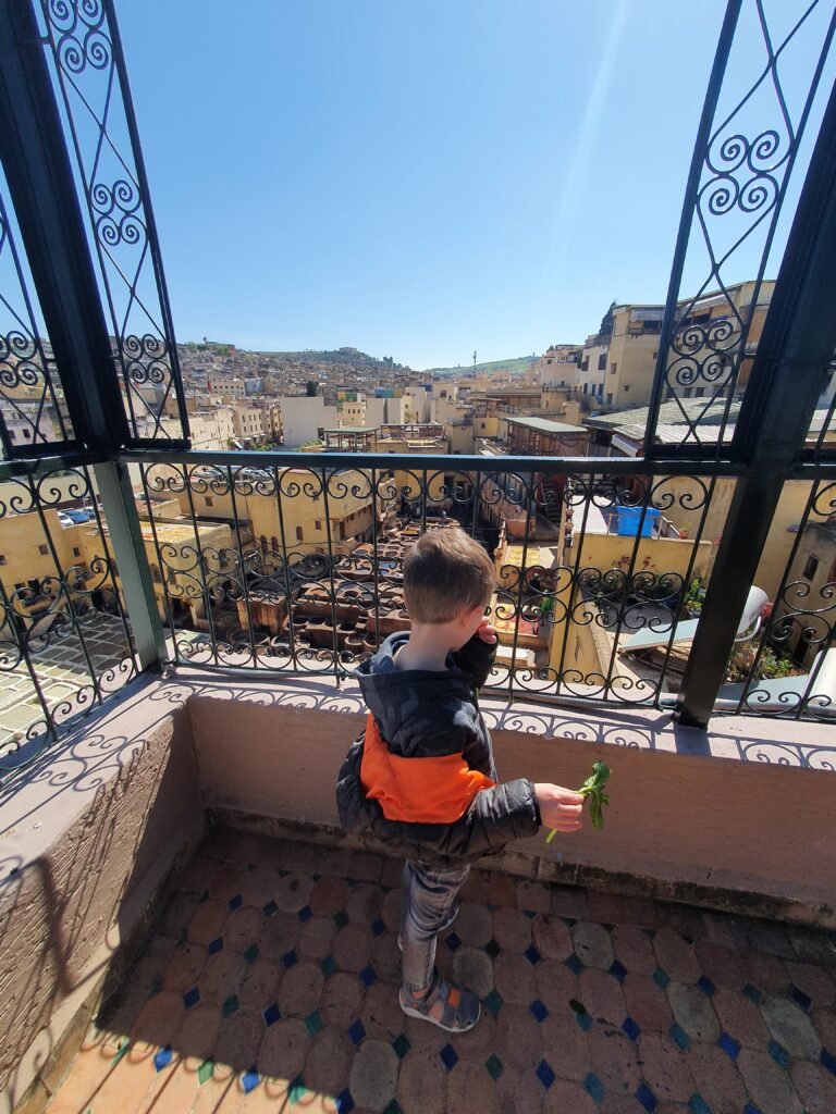 Boy on a balcony overlooking the rooftops of a Moroccan medina