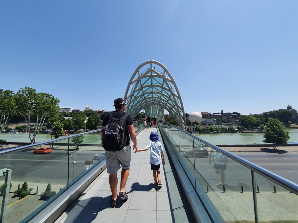 Father and son walking across the Bridge of Peace in Tbilisi, Georgia