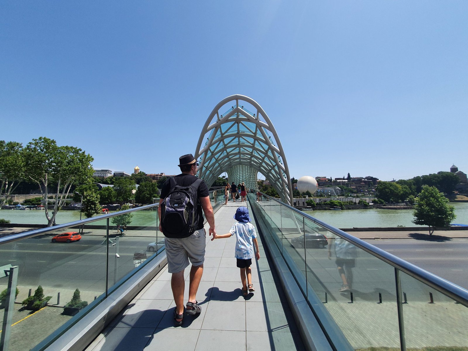 Father and son walking across the Bridge of Peace in Tbilisi, Georgia