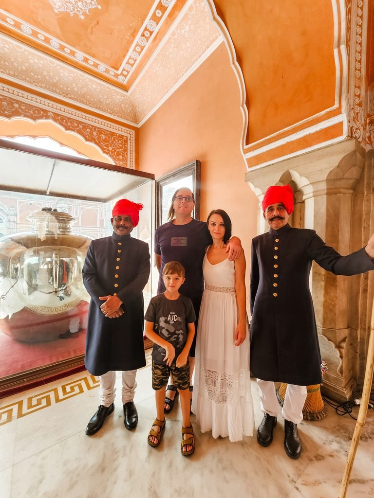 Our family with two palace guards in red turbans inside an ornate palace in India