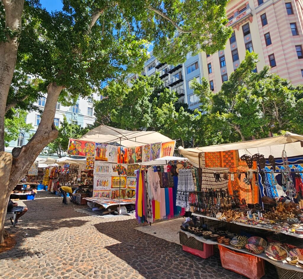 Outdoor craft market stalls selling colourful textiles under the trees