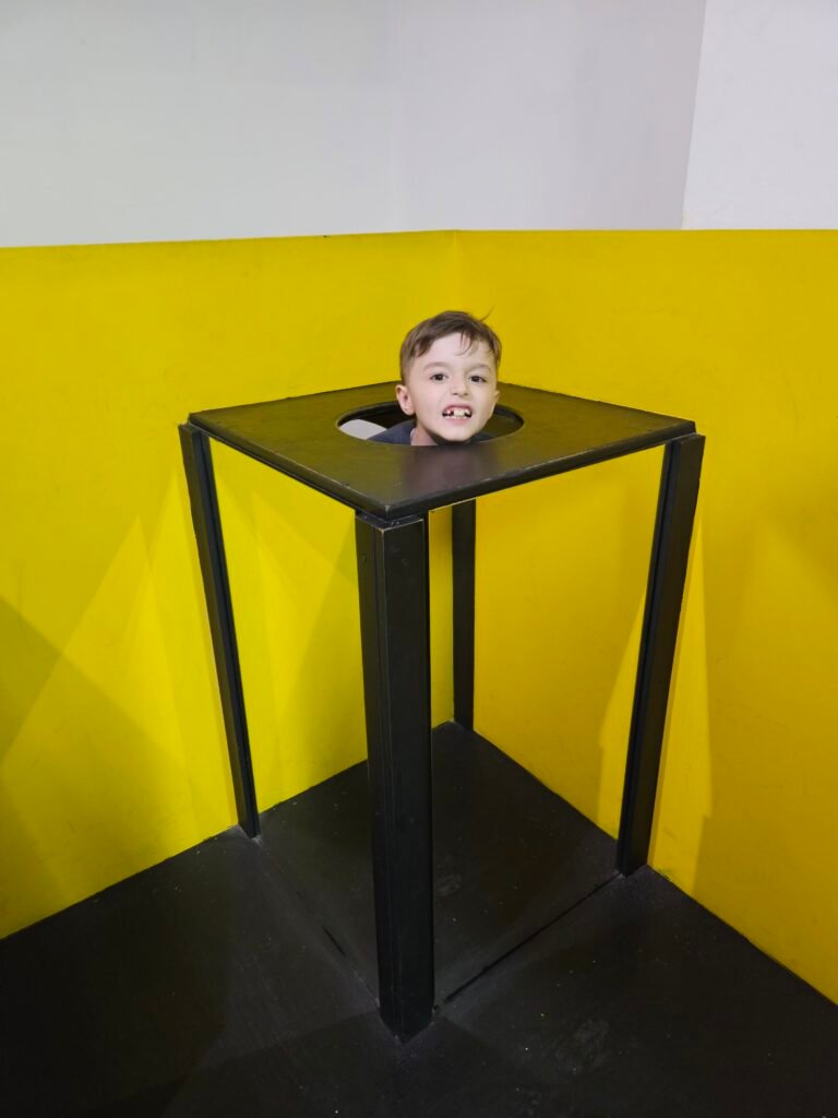 Child posing for a head-on-a-table illusion at an illusion museum