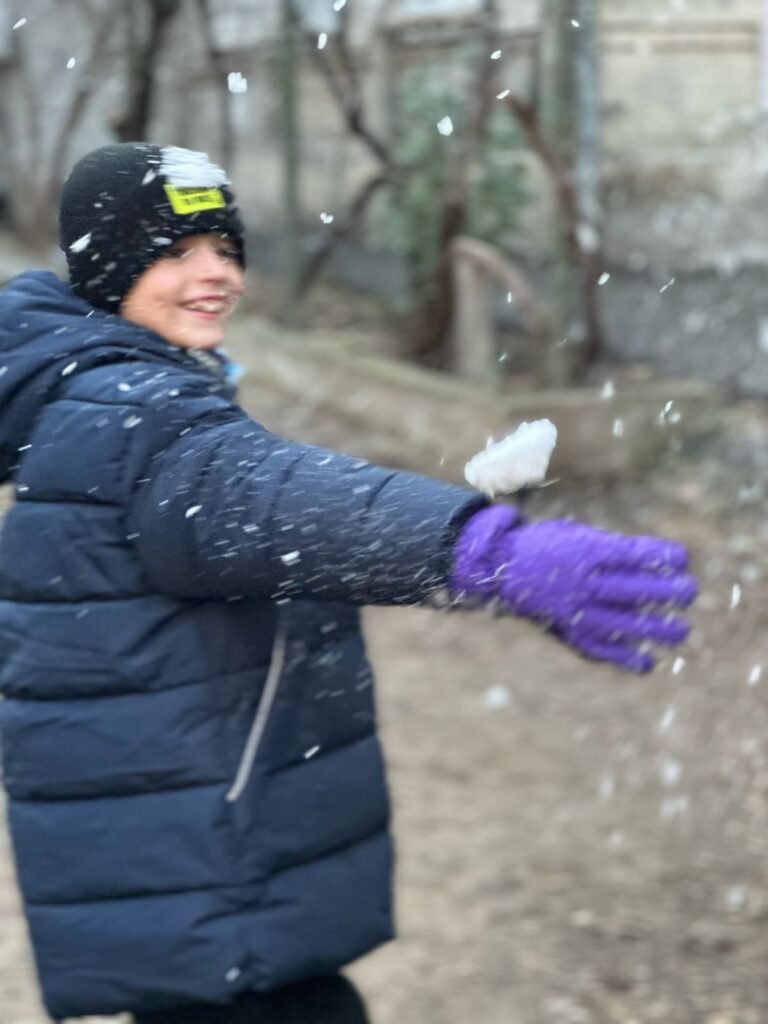 Boy in a winter coat throwing a snowball